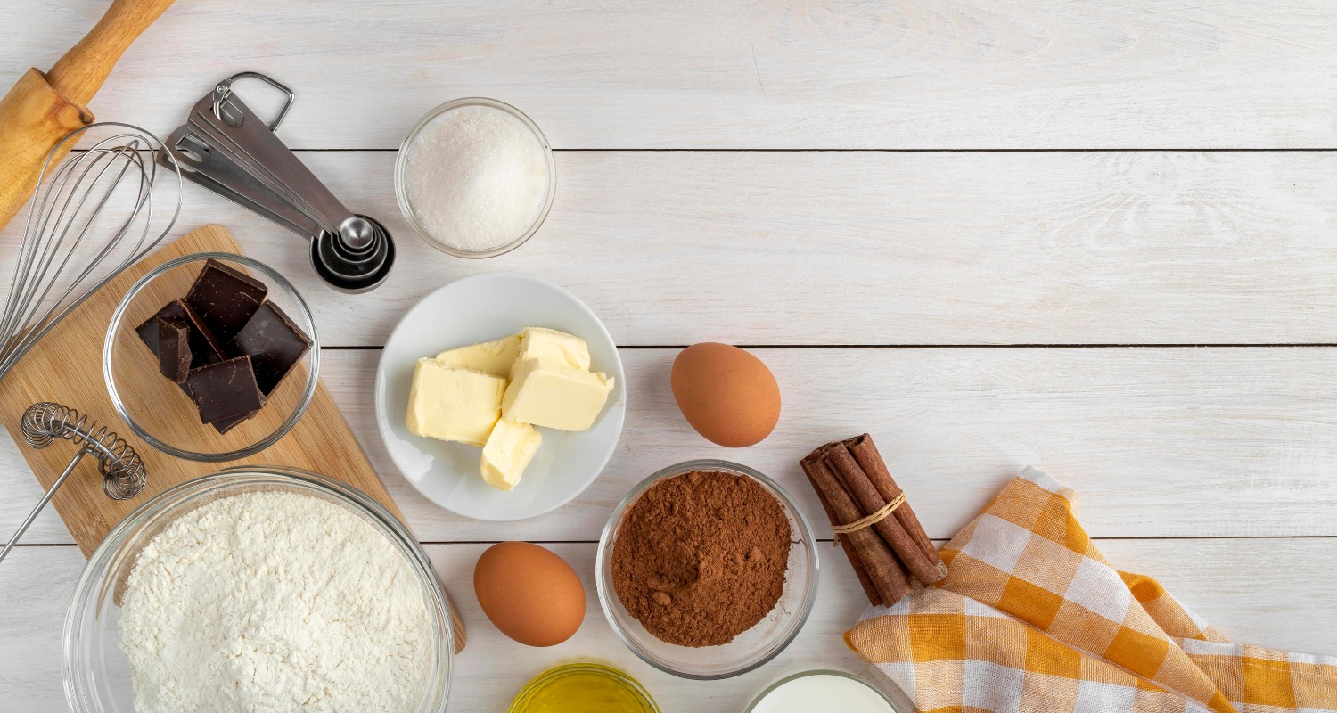 Flatlay of puff pastry ingredients including flour, unsalted butter, ice water, and a pinch of salt on a rustic wooden table.