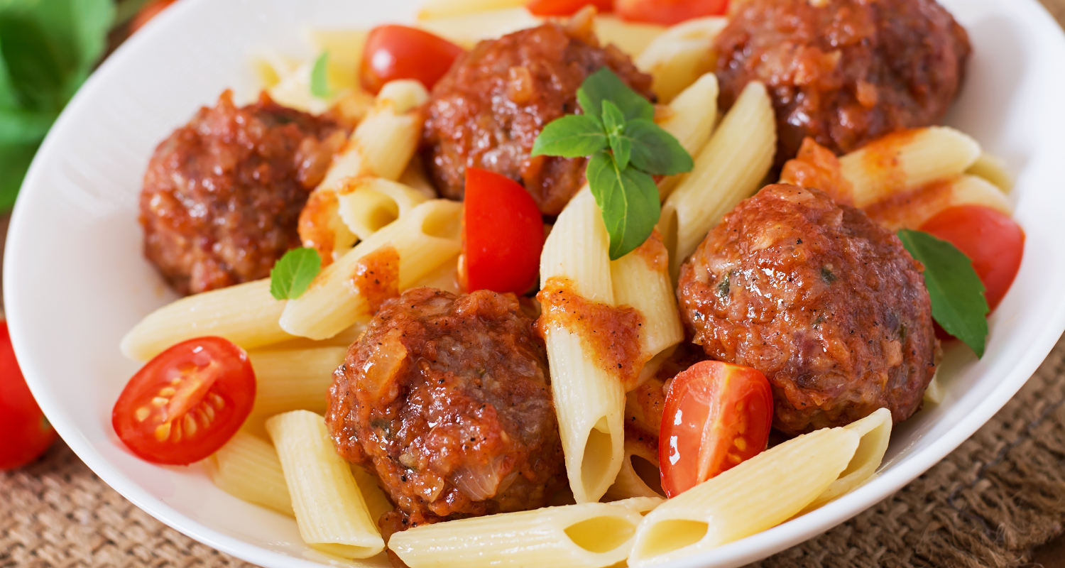 Hearty Polish sausage pasta dish in a white bowl, satisfying your cravings with rich flavors.